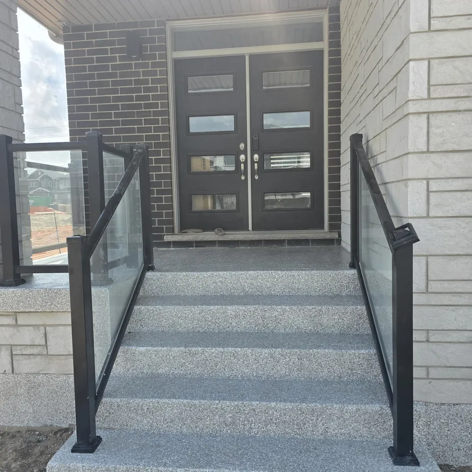 Entry steps with glass railings finished in a grey speckled coating