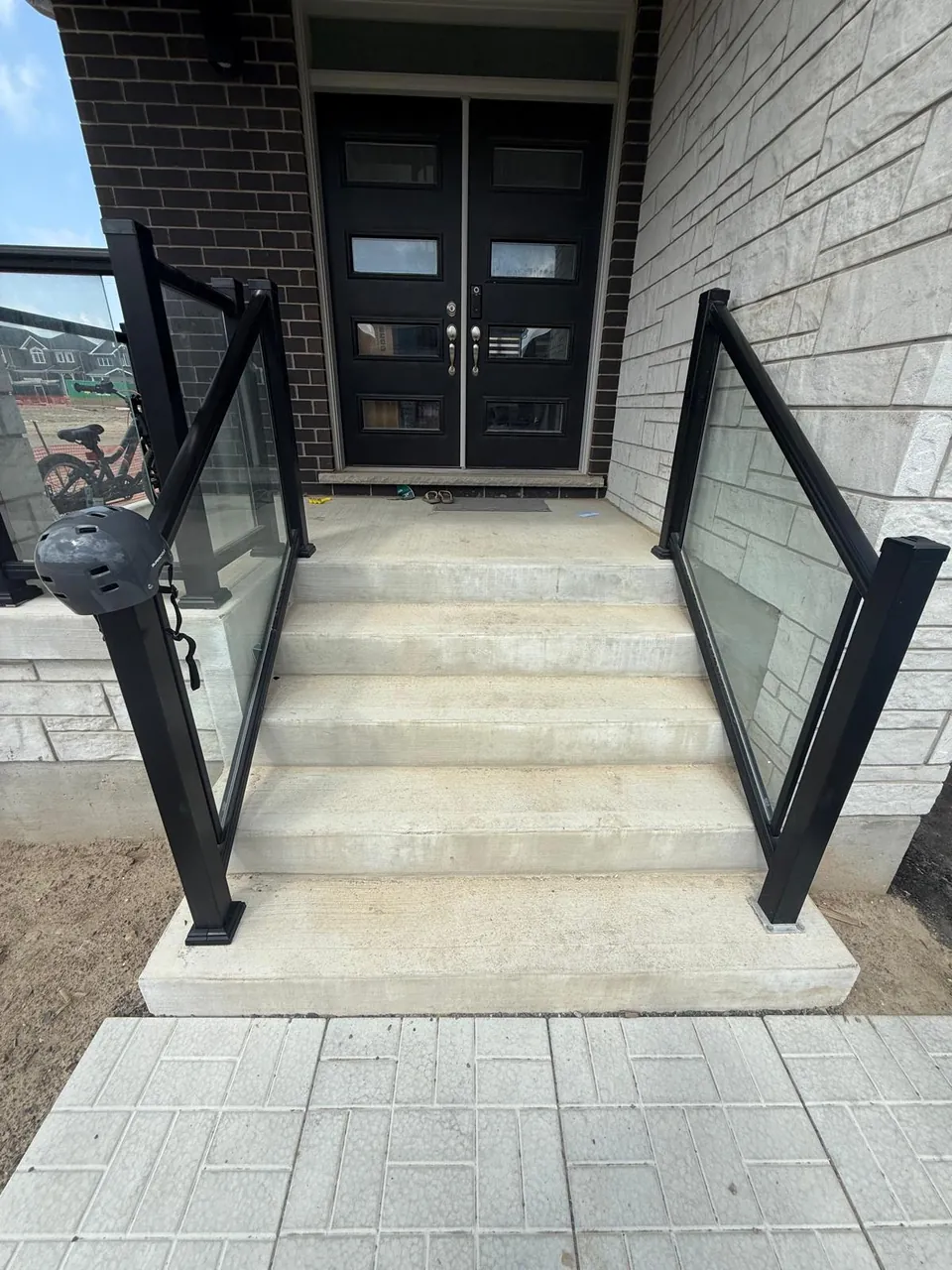Bare concrete entry steps with glass railings before coating
